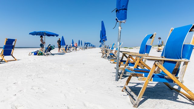 A picnic pavilion and concession store stand on a white sand beach.