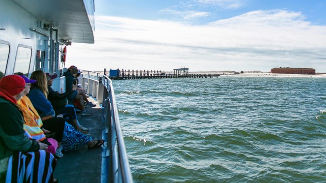 Visitors walk toward the camera down the dock at Ship Island.