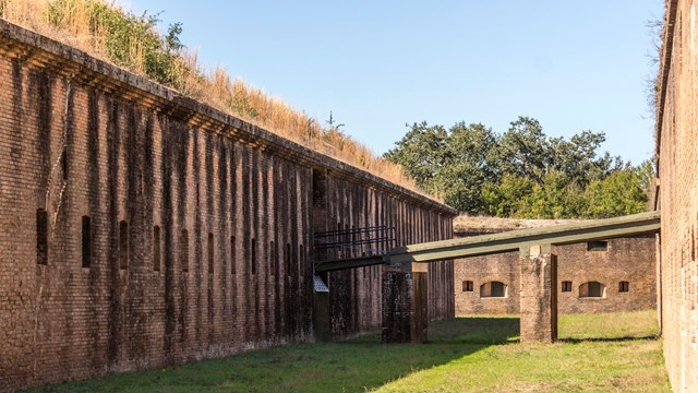 Masonry walls raise on both sides, a drawbridge connects the two.