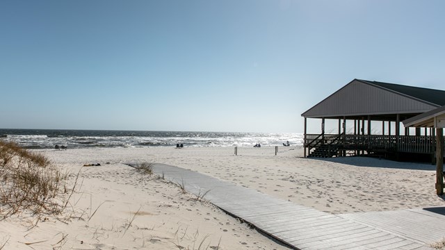 A pavilion and beach mat are found on an empty beach.