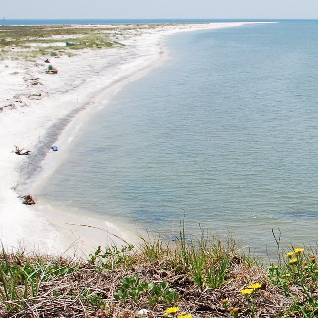 A white sand barrier island extends away from the camera, there is blue water on either side.