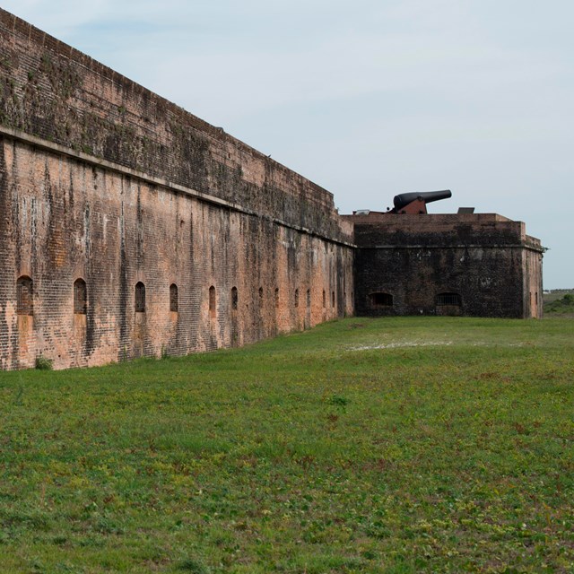 A historic cannon sits atop an historic fortification on a barrier island.