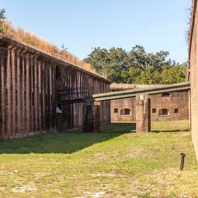 Masonry walls raise on both sides, a drawbridge connects the two.