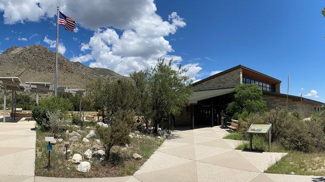 View of a sidewalk and flagpole in front of a stone building