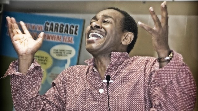 A man wearing a red & white polka dot shirt with hands in the air. 