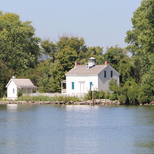 A white clapboard house with a lighthouse on top.