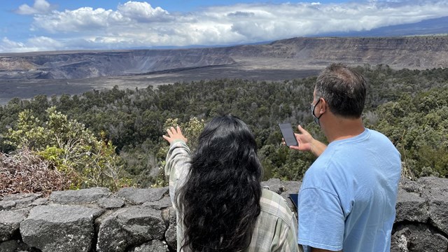 Visitors stand at the edge of a crater