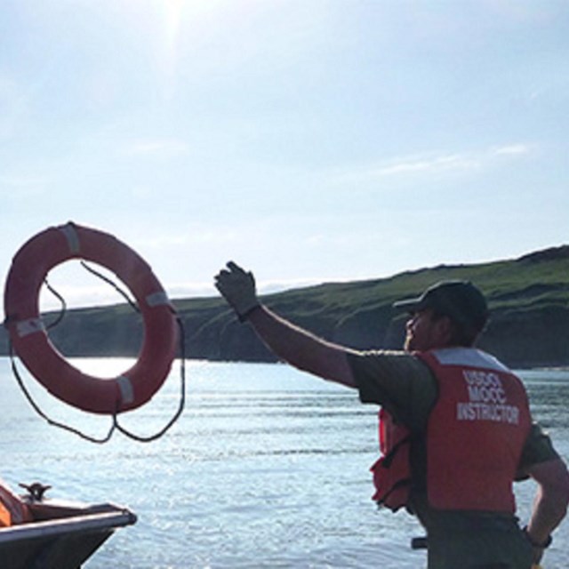 Man wearing life jacket throwing life preserver ring