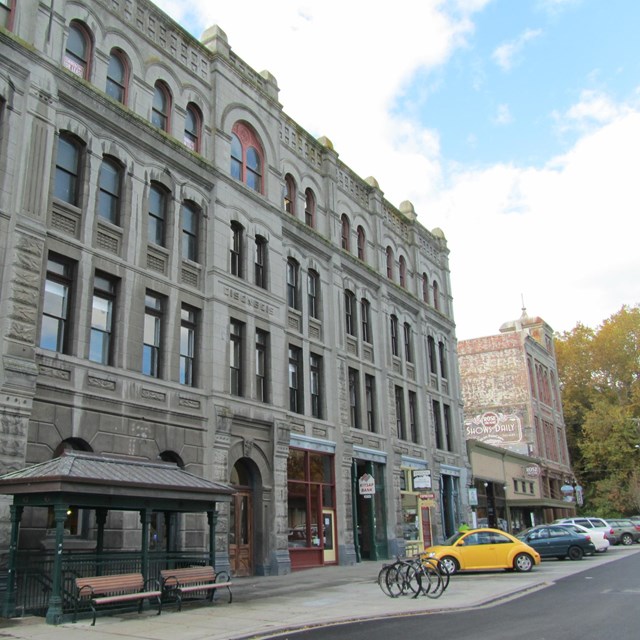 Stone building with streetscape and blue sky.