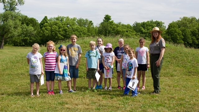 a group of children pose with a park ranger.