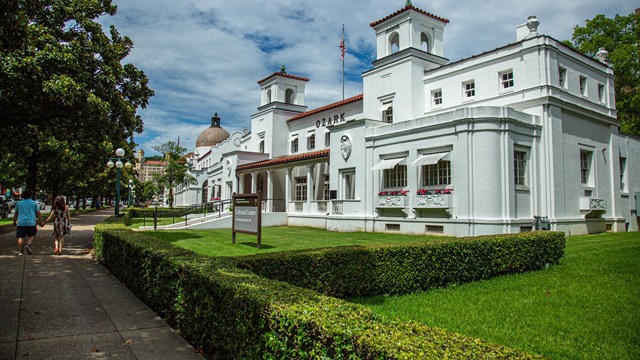 Looking at the Ozark Bathhouse. The building is white with a Spanish hacienda architecture style.