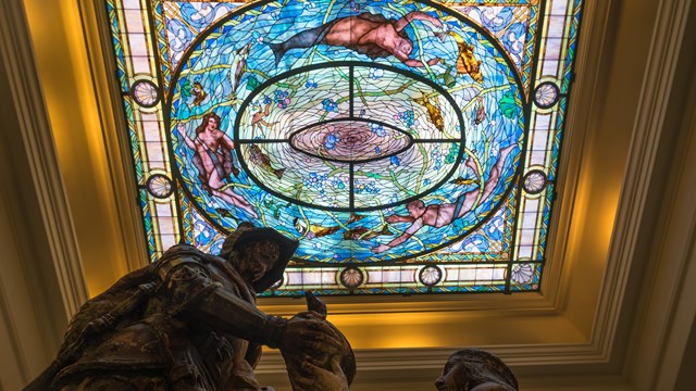 A worm's eye view of an ornate colorful stained glass ceiling.