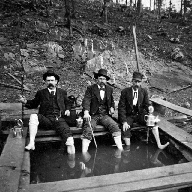 Three men from the mid-1800s are soaking in Corn Hole Spring.