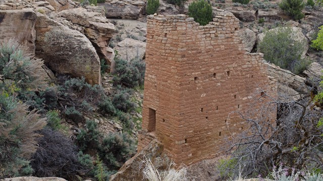 a tall, rectangular stone tower perched on a boulder