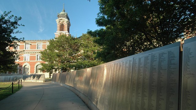 mural of flat stone with names and an old red brick building with a tower in the background