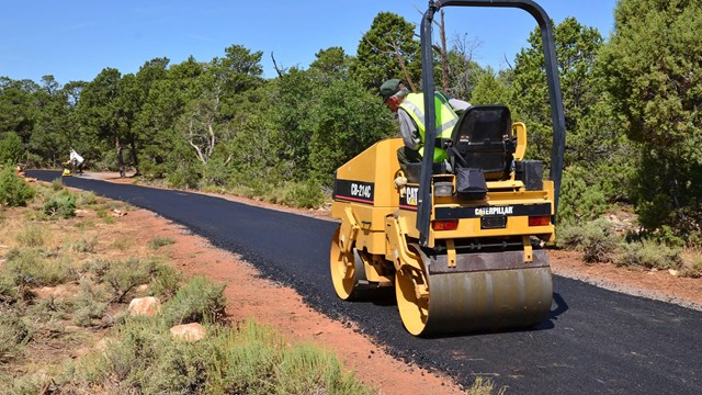 Maintenance worker driving a machine repaving a road