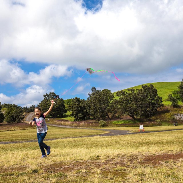 Kids running with kites in a grass field