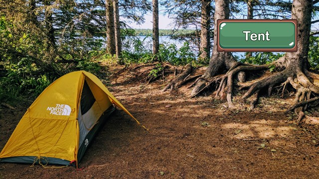 A yellow tent set up at a lakeside campsite.