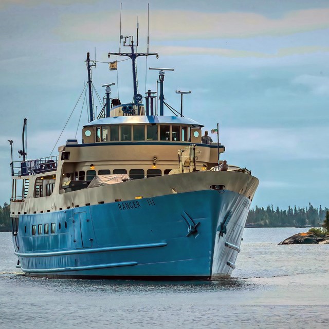 Ranger III sailing in Rock Harbor Channel. A rocky island sits to the right of the vessel.