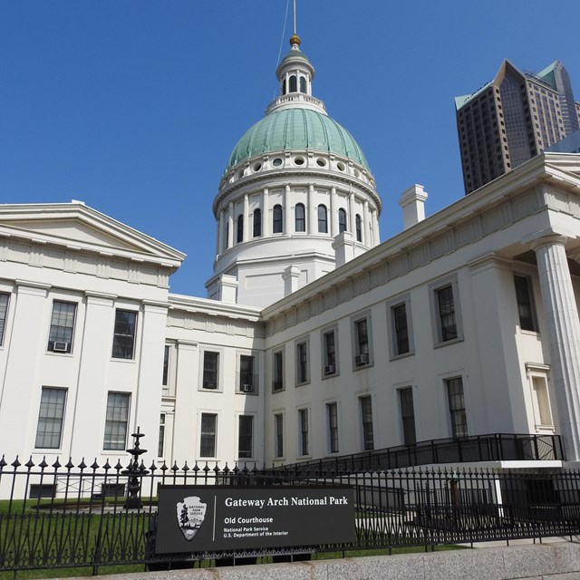 A white building with a green dome at the top