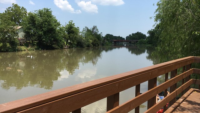 View of dock and bayou with a partially cloudy sky.