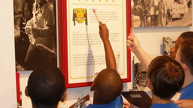 Boys point at a Mardi Gras exhibit