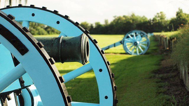 Cannons lined up behind wood and mud rampart