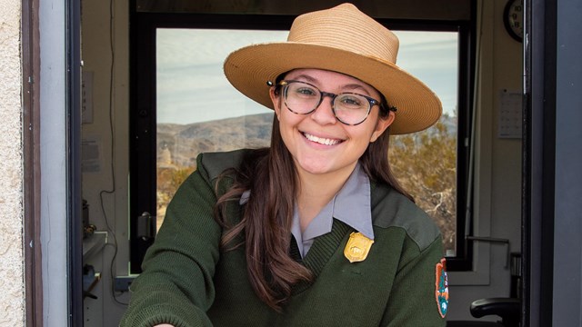  a fees ranger smiling while holding a brochure out of a fees booth 