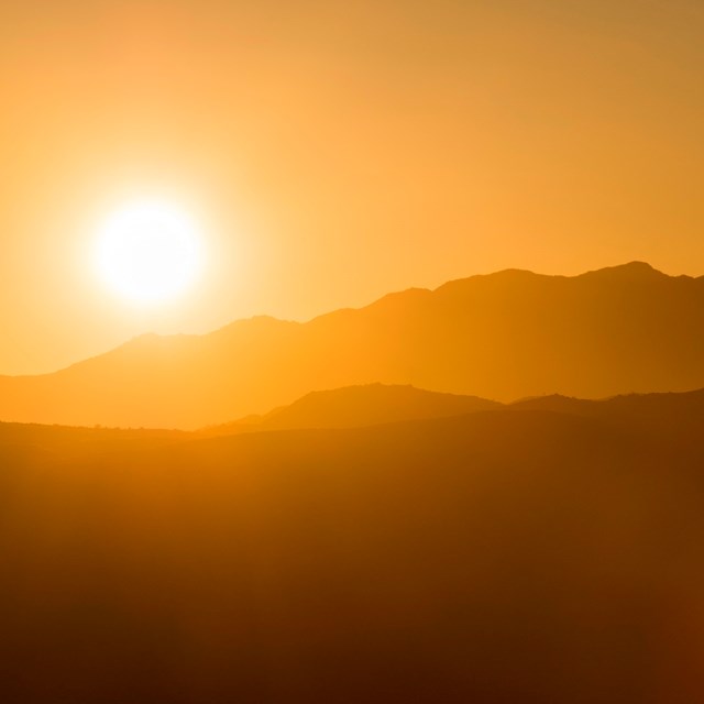 A sunsetting over silhouetted mountains.