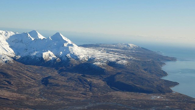 Snow covered mountains next to ocean coast.