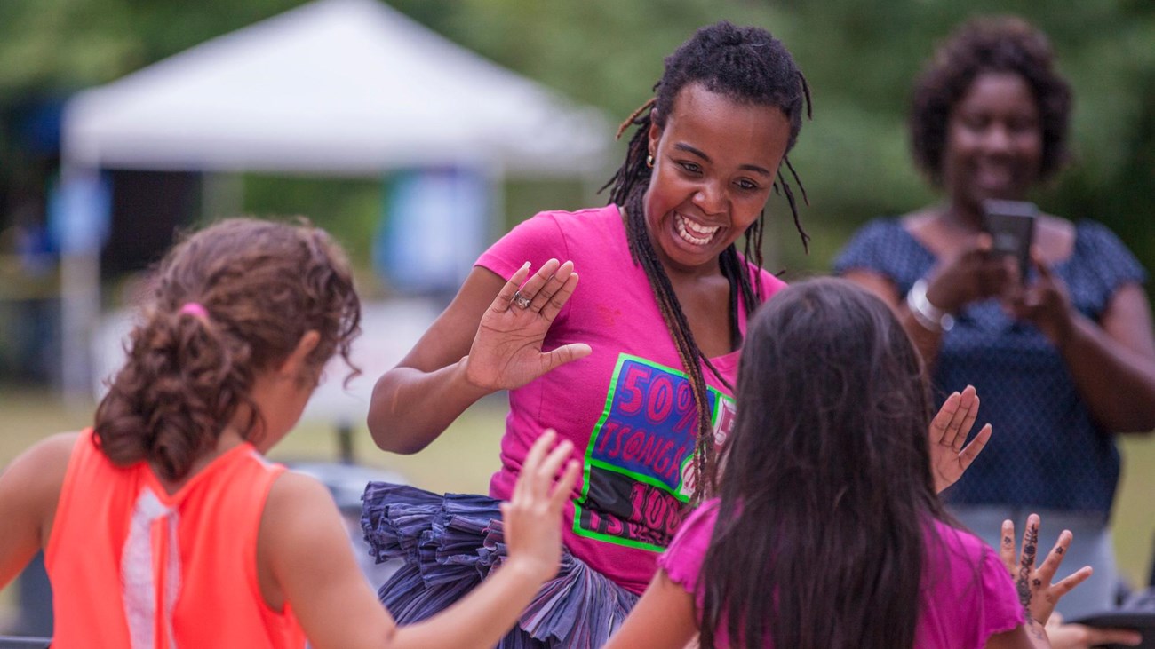A woman laughs while dancing with two girls