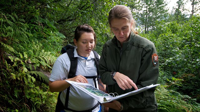 Two people look through a binder on the trail