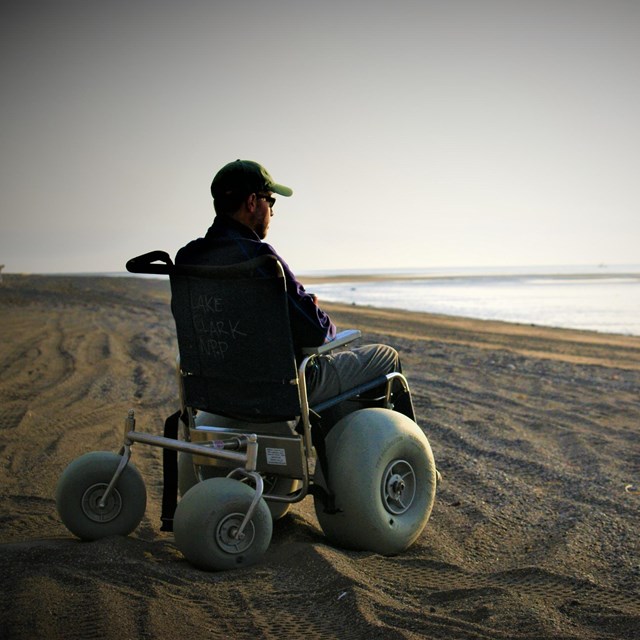 a man sitting in a dune buggy wheelchair on the beach