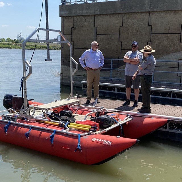 three men stand near a boat