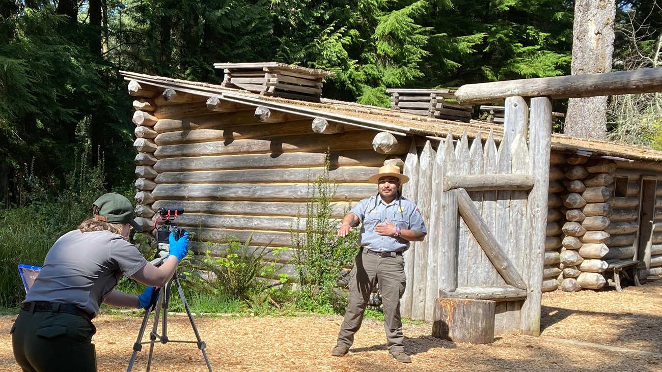 One ranger filming another ranger presenting in front of Fort Clatsop