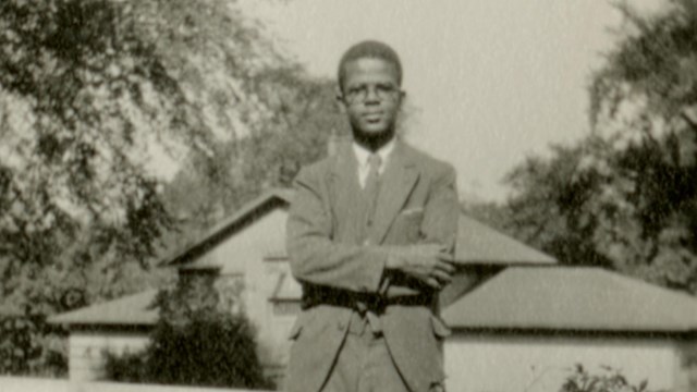 Candid portrait of a Black man standing outside on a porch.