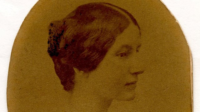 Portrait of a white woman. Head and shoulders in nearly full profile to subject's left