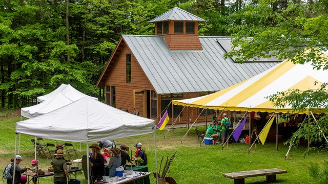 View from above of large event on lawn with tents and people walking around