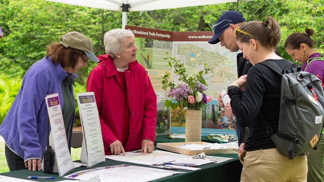 two volunteers help two visitors at an event booth