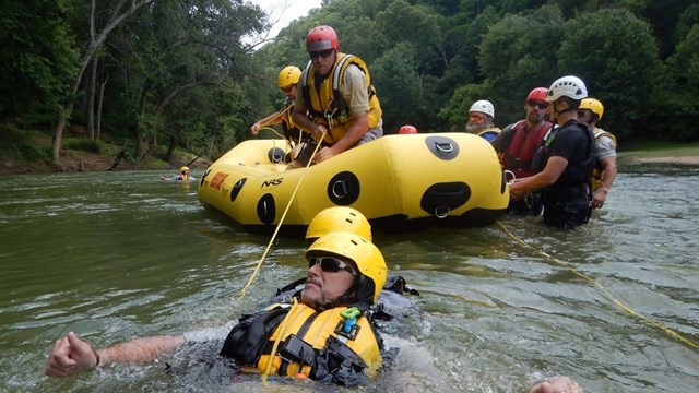 Park personnel in life jackets perform river rescue training.