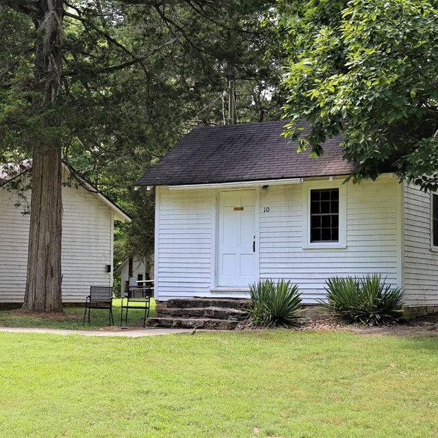 Two small white cabins in a green field. 