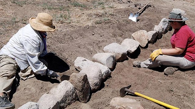 Image of volunteers moving a wheelbarrow of weeds