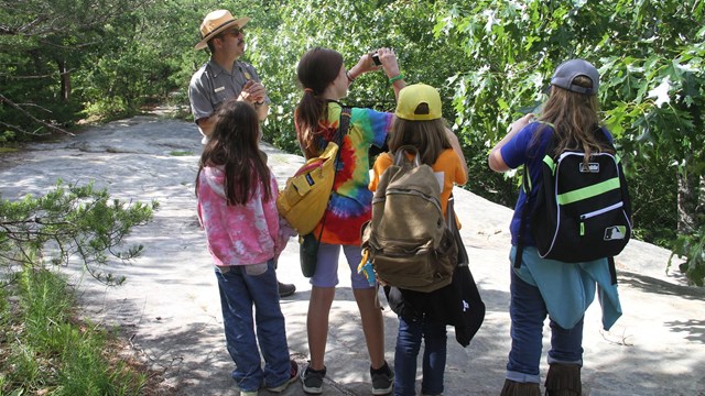 A ranger and four children on an outdoor trail. 