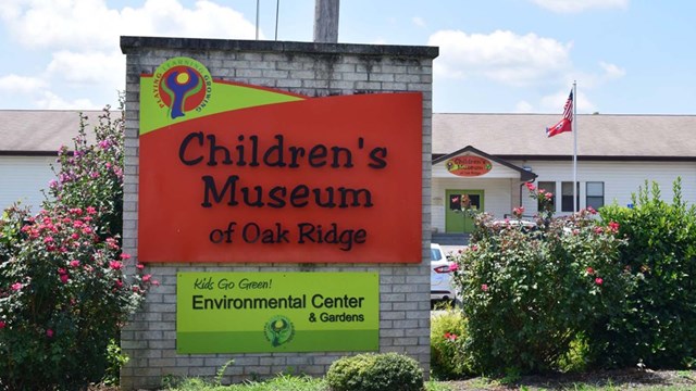 An orange and yellow sign on a stone says, "Children's Museum of Oak Ridge."