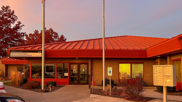 Red-roofed single-level building with a sign that reads "Manhattan Project National Historical Park"