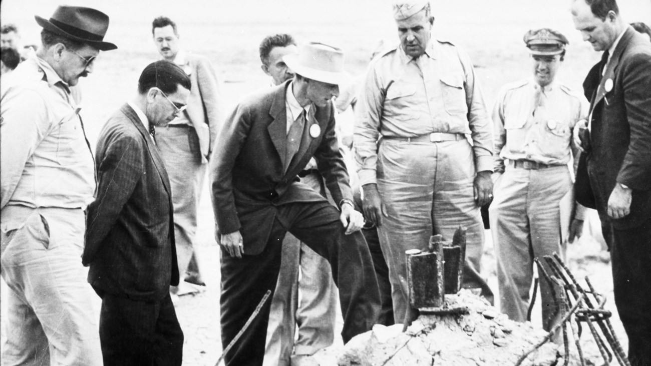 A black and white photo of a group of men looking down at the ground.