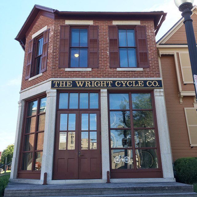 A two-story brick building with tall windows and shutters on them with sign 