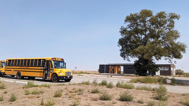 A yellow school bus is parked in front of the Minidoka Visitor Center.