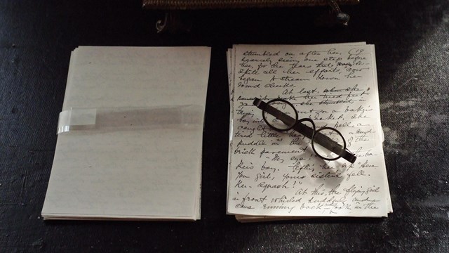 Two sheets of paper side by side, left one blank, right with writing and antique glasses on it.