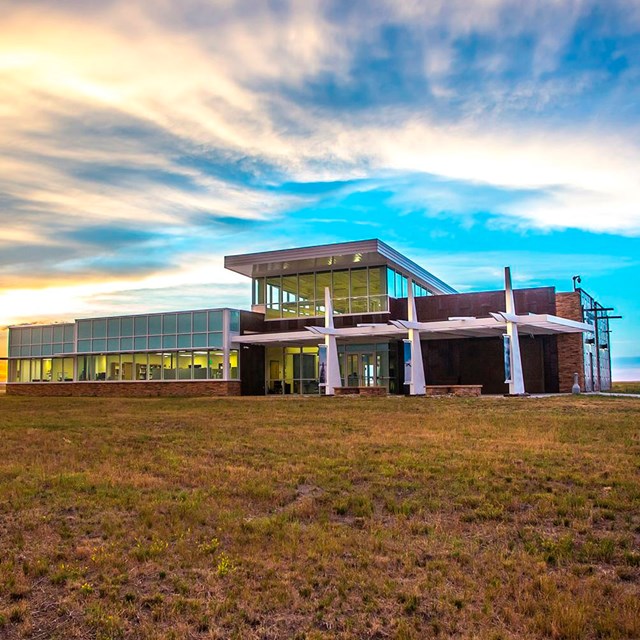 A concrete walk leads to a glass and steel building